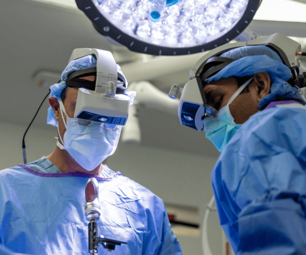A surgeon wears an augmented reality headset to perform spine surgery