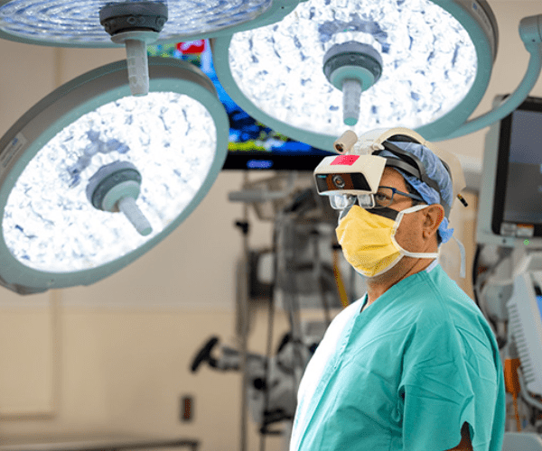 A surgeon wears an AR headset to perform spine surgery